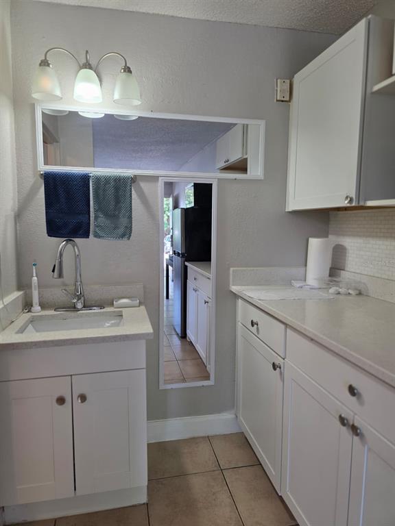 A bathroom vanity with a sink, white cabinets, and a mirror on a gray wall — 7900 S ORANGE BLOSSOM TRAIL UNIT 1055, ORLANDO, FL