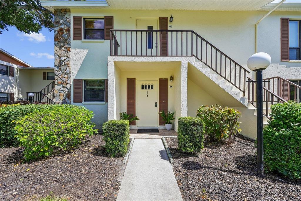 An exterior view of a two-story apartment building with a concrete walkway and stairs — 5400 34TH STREET W UNIT A6, BRADENTON, FL