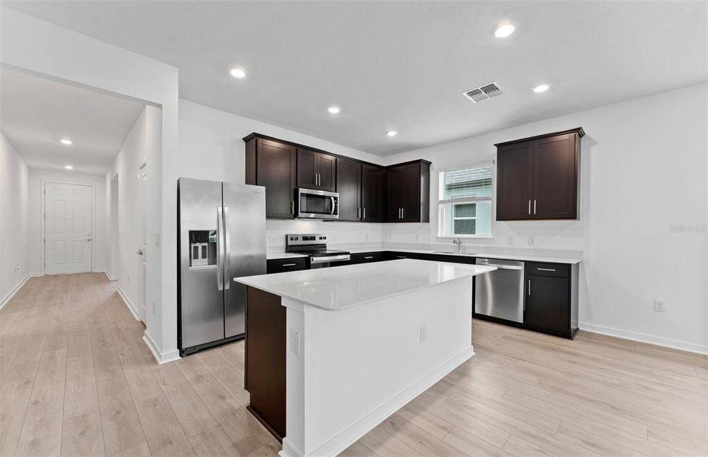 A living room with a gray sofa and coffee table opens to a modern kitchen — 4278 OBSIDIAN DRIVE, SPRING HILL, FL