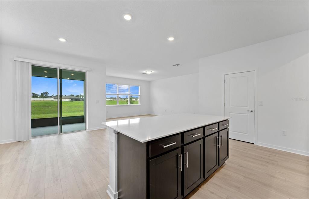 A kitchen with white cabinets, a large island, stainless steel appliances, and an adjacent dining area — 4278 OBSIDIAN DRIVE, SPRING HILL, FL