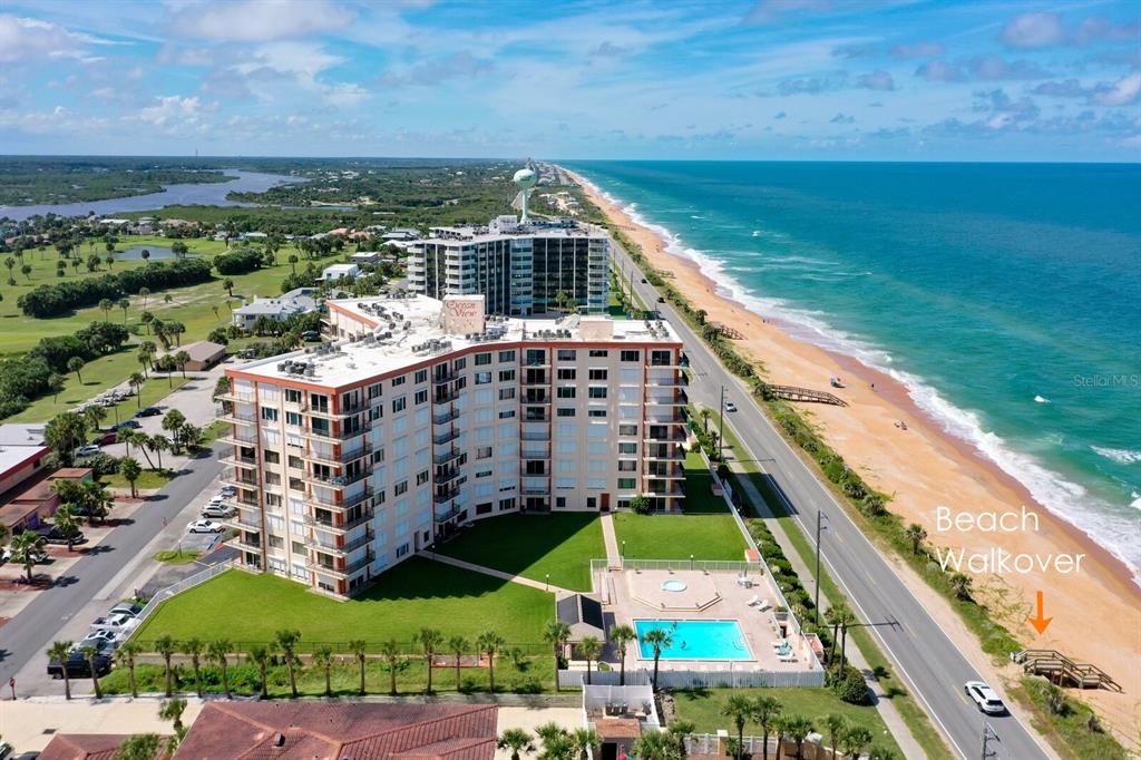 An aerial view shows a multi-story beachfront condominium building with a pool and beach access — 3600 S OCEAN SHORE BOULEVARD UNIT 214, FLAGLER BEACH, FL