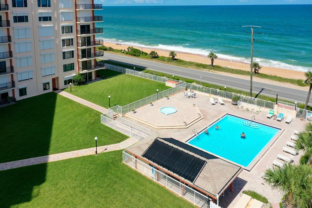 An aerial view of a beachfront condominium complex featuring a swimming pool and grassy lawn — 3600 S OCEAN SHORE BOULEVARD UNIT 214, FLAGLER BEACH, FL