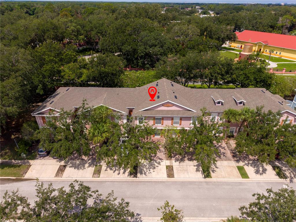 An aerial view shows a pink multi-unit townhouse building with a brown shingled roof — 2328 CARAVELLE CIRCLE, KISSIMMEE, FL