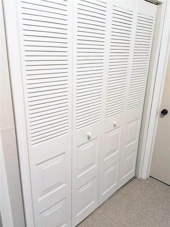 White louvered bifold closet doors are installed in a room with beige carpet — 6640 121ST AVENUE UNIT 1, LARGO, FL
