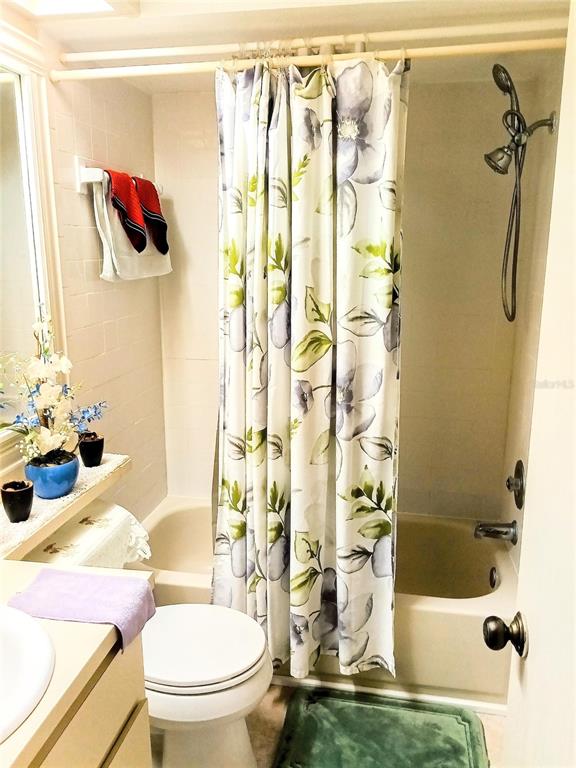 A bathroom features a floral shower curtain, a white toilet, and a wall-mounted shower head — 6640 121ST AVENUE UNIT 1, LARGO, FL