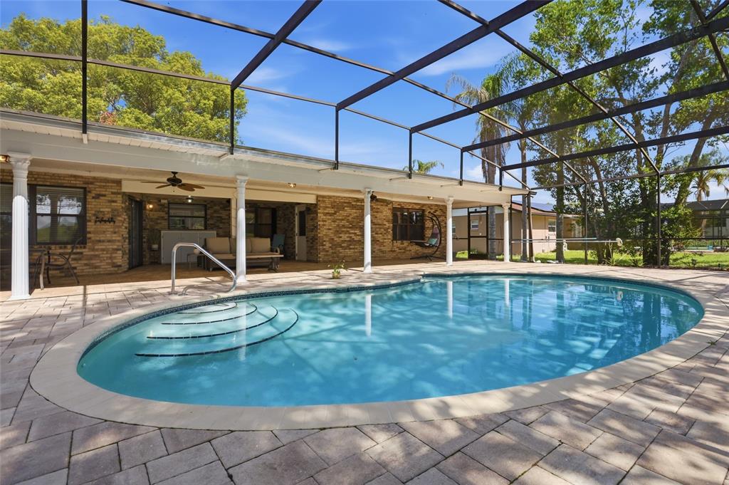 A backyard swimming pool with a screened enclosure and a covered brick patio area — 2249 E UNION CIRCLE, DELTONA, FL