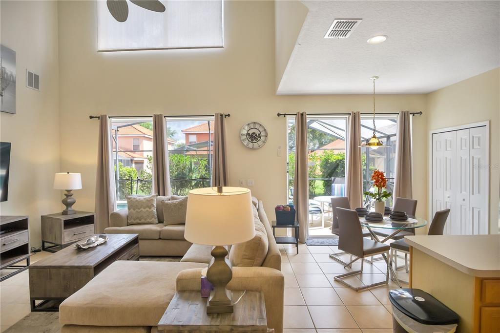 A living and dining area with high ceilings, tile floors, and sliding glass doors to a patio — 134 SEVILLA AVENUE, DAVENPORT, FL