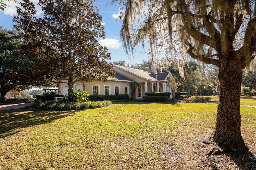 A tan house with a brick driveway and a large tree with Spanish moss — 11715 NW 90TH AVENUE, REDDICK, FL