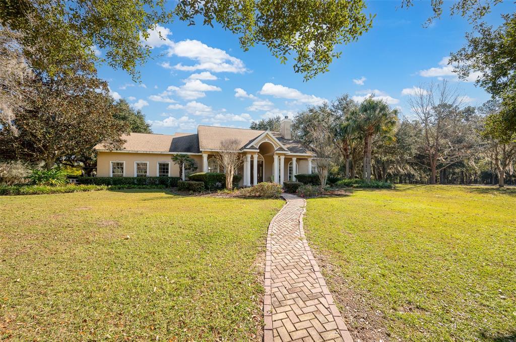 A single-story house with a brick walkway leading to a columned entrance on a lawn — 11715 NW 90TH AVENUE, REDDICK, FL