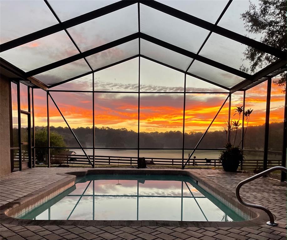 A large house sits in the distance behind a vast, grassy lawn with mature trees — 11715 NW 90TH AVENUE, REDDICK, FL