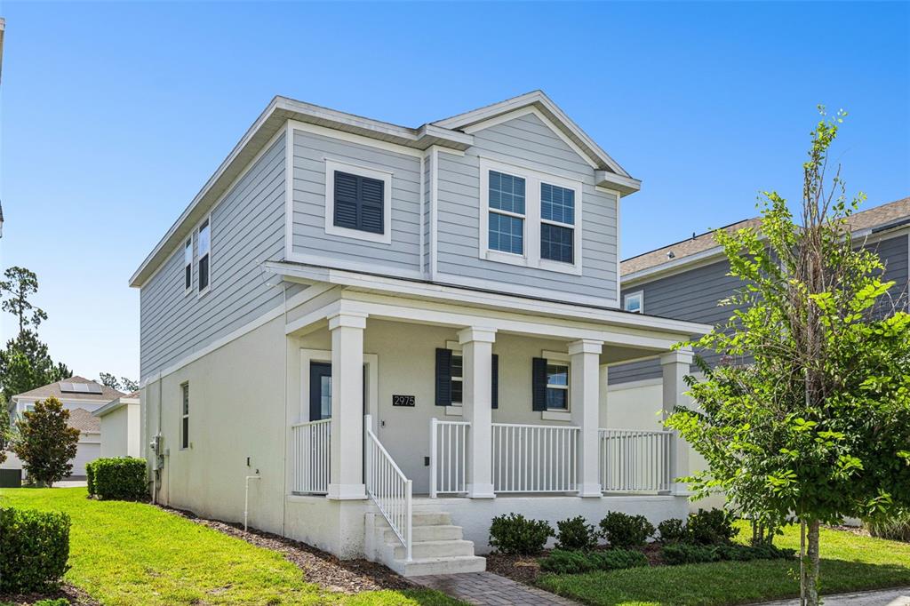 A two-story house with light blue siding, a front porch, and white railings — 2975 ADDISON BOULEVARD, ST CLOUD, FL