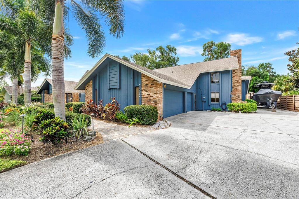 A blue house with a brick chimney and a boat parked in the driveway — 2837 SABER DRIVE, CLEARWATER, FL
