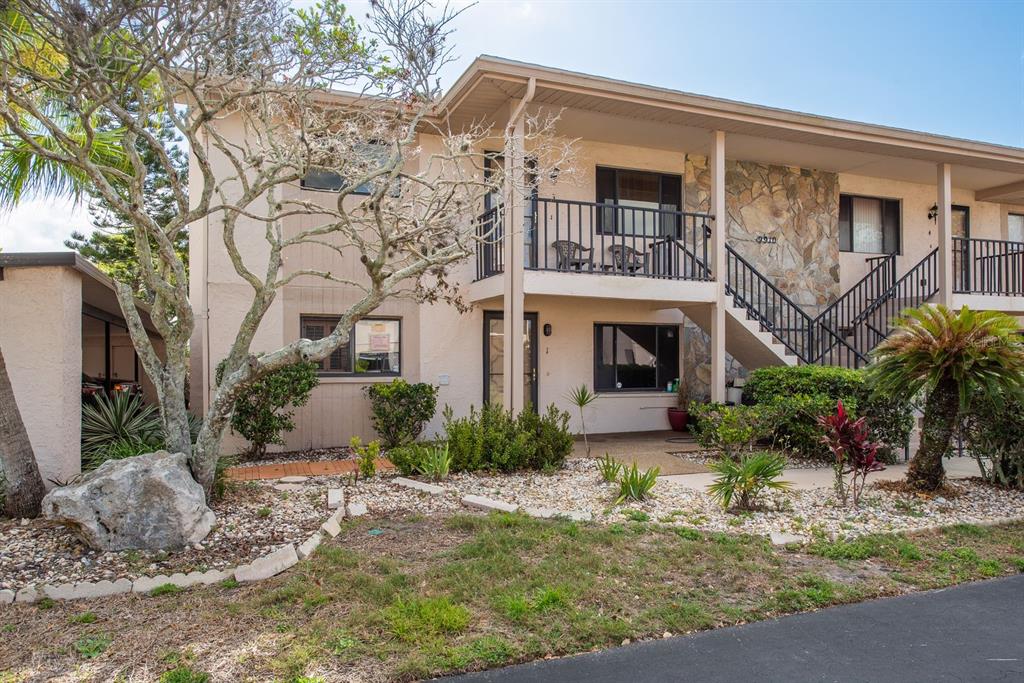 A two-story apartment building with a stone facade, a balcony, and a landscaped front yard — 9910 EAGLES POINT CIRCLE UNIT 3, PORT RICHEY, FL