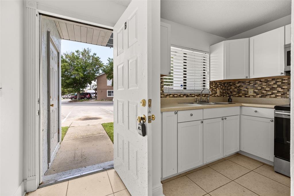 A white two-story townhouse exterior features two gray entry doors and a small concrete walkway — 111 MICHELLE LANE UNIT B, KISSIMMEE, FL