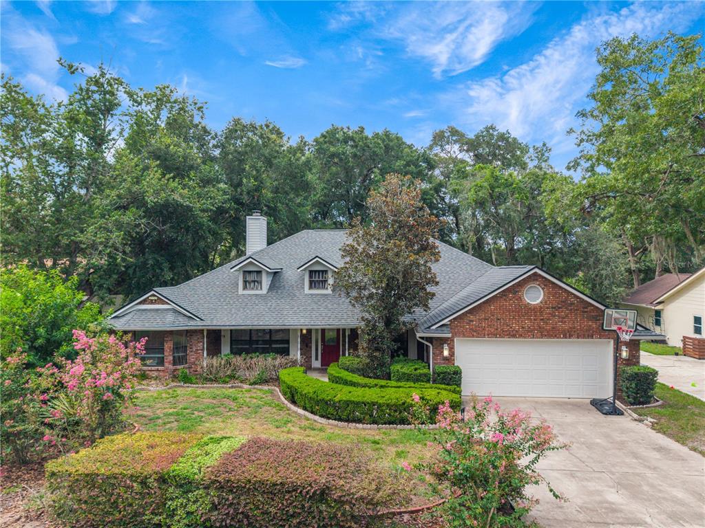 A single-story brick house with a two-car garage, dormer windows, and manicured landscaping — 1937 HIDDEN PINE LANE, APOPKA, FL