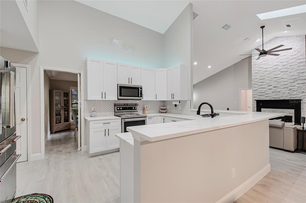 A spacious living room features light wood flooring, a gray sectional sofa, and vaulted ceilings — 1937 HIDDEN PINE LANE, APOPKA, FL