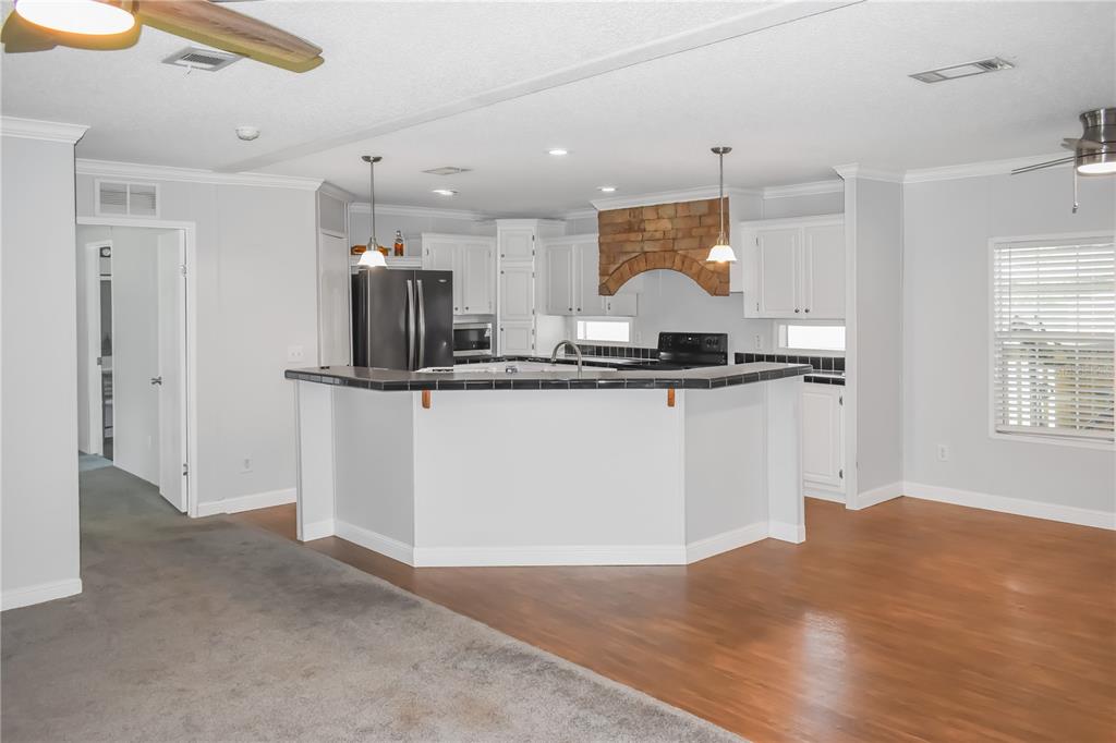 A kitchen with white cabinets, a brick range hood, and a tiled breakfast bar island — 10851 NE 76TH STREET, BRONSON, FL