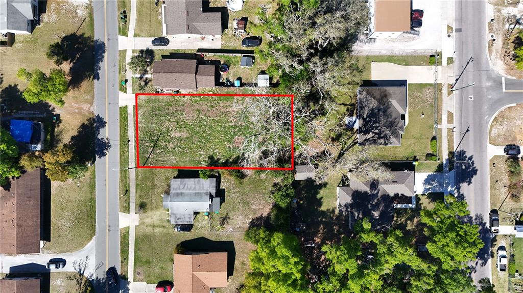 This aerial view shows a vacant, rectangular residential lot outlined in red — E HAZZARD, EUSTIS, FL