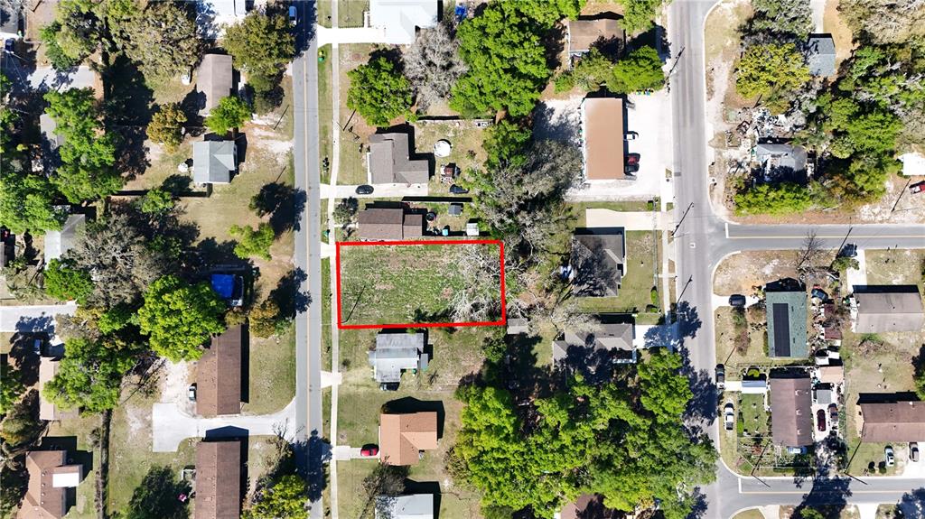 This aerial view shows a vacant, rectangular lot outlined in red within a residential neighborhood — E HAZZARD, EUSTIS, FL