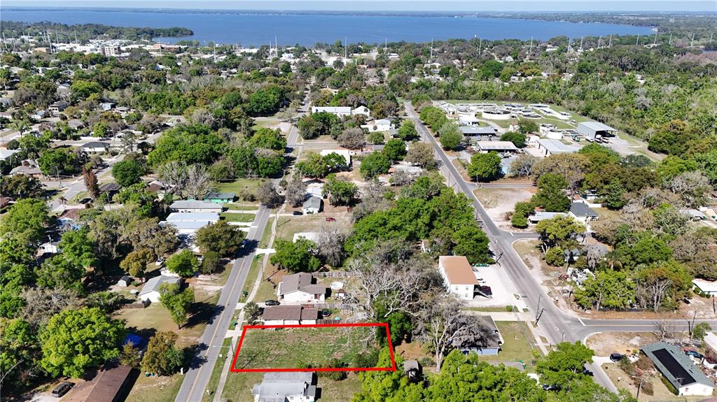 An aerial view shows a vacant rectangular lot outlined in red within a residential neighborhood — E HAZZARD, EUSTIS, FL