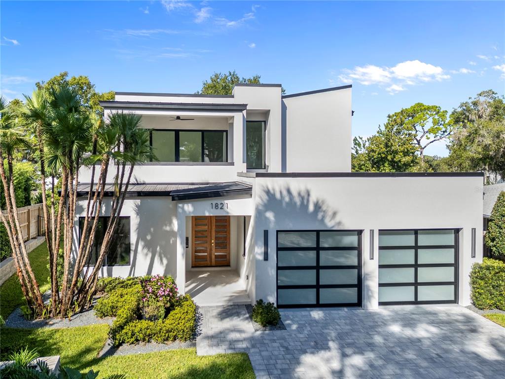 A modern two-story house exterior features a wooden double front door and palm trees — 1821 ENGLEWOOD ROAD, WINTER PARK, FL