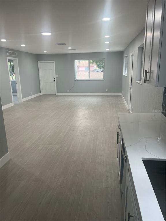 A bright, open-concept living area features light gray walls, wood-look flooring, and recessed lighting — 836 SW 2ND TERRACE, DEERFIELD BEACH, FL