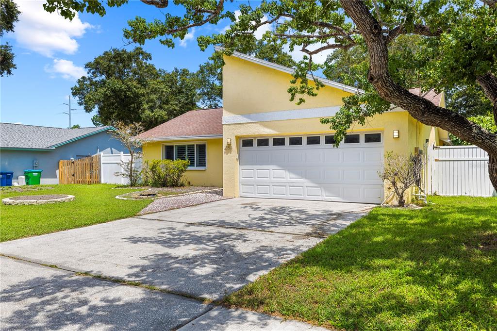A yellow single-story house with a white garage door and a concrete driveway — 2158 KARAN WAY, CLEARWATER, FL