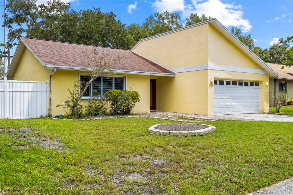 A yellow single-story house with a brown shingled roof, white garage door, and front lawn — 2158 KARAN WAY, CLEARWATER, FL