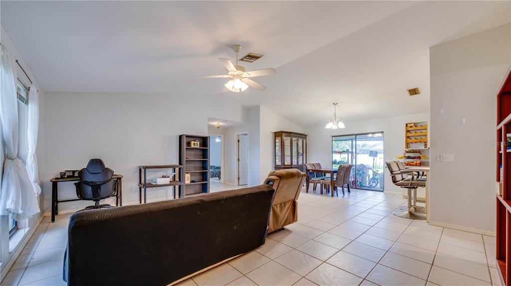 An open-concept living and dining area features tiled floors, a ceiling fan, and sliding doors — 3609 SE 2ND PLACE, CAPE CORAL, FL