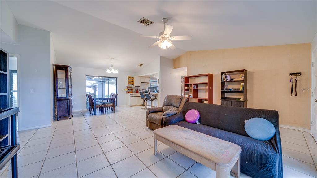 An open-concept living and dining area features white tile flooring, a ceiling fan, and furniture — 3609 SE 2ND PLACE, CAPE CORAL, FL