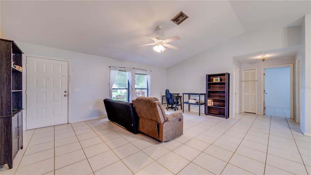 A living room with tile flooring, a ceiling fan, a couch, and a desk area — 3609 SE 2ND PLACE, CAPE CORAL, FL