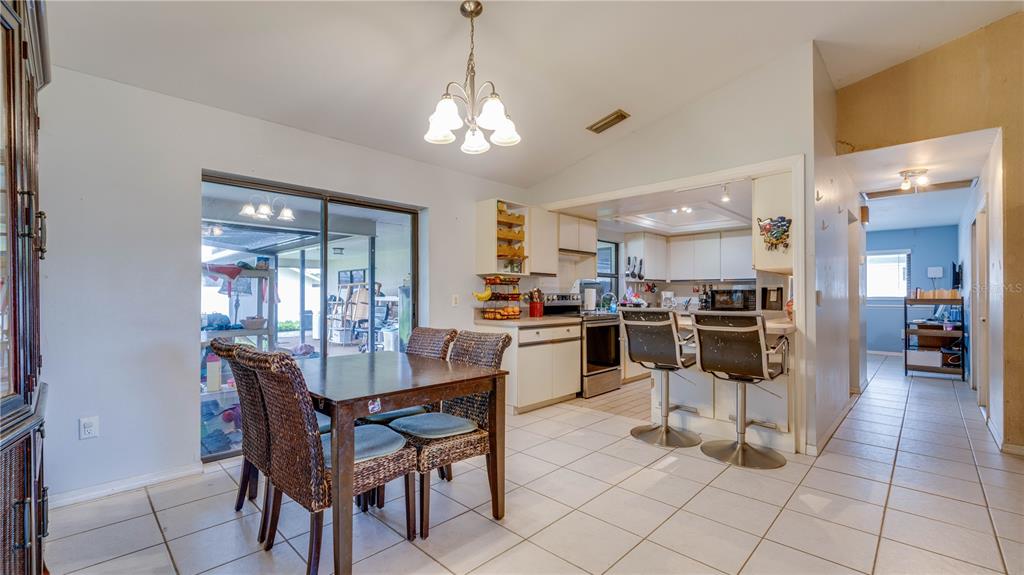 A dining area with a wicker chair set sits adjacent to an open-concept kitchen — 3609 SE 2ND PLACE, CAPE CORAL, FL