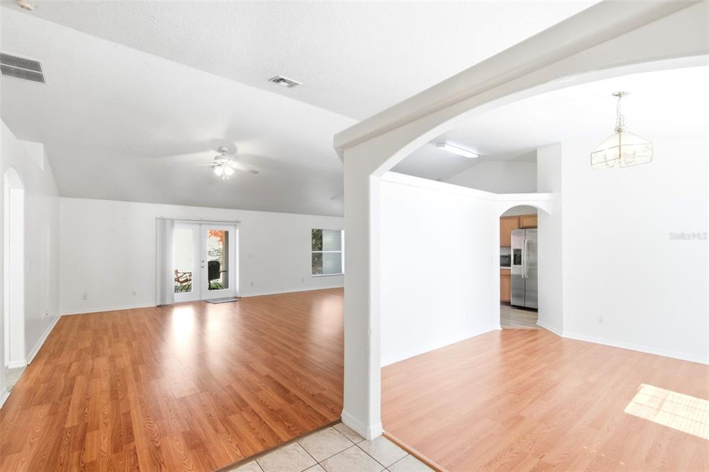 An open-concept living and dining area with light wood flooring and white walls — 10320 VISTA PINES LOOP, CLERMONT, FL