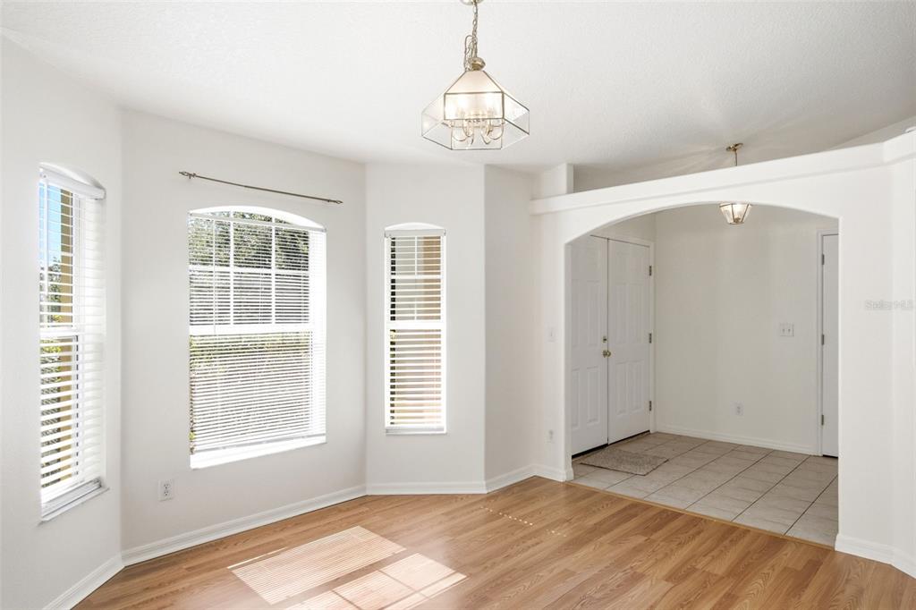 A dining area with wood flooring, a chandelier, and an arched entryway to a tiled foyer — 10320 VISTA PINES LOOP, CLERMONT, FL