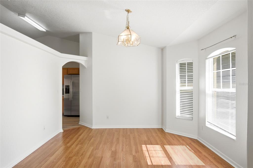 A dining area with wood-look flooring, a chandelier, and an arched entryway to the kitchen — 10320 VISTA PINES LOOP, CLERMONT, FL