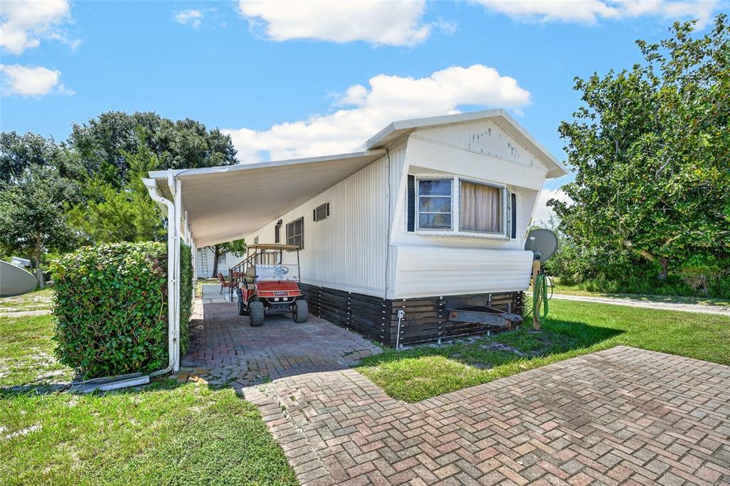 A white mobile home with a brick-paved carport and a golf cart parked underneath — 13651 NE 237TH COURT, FORT MC COY, FL