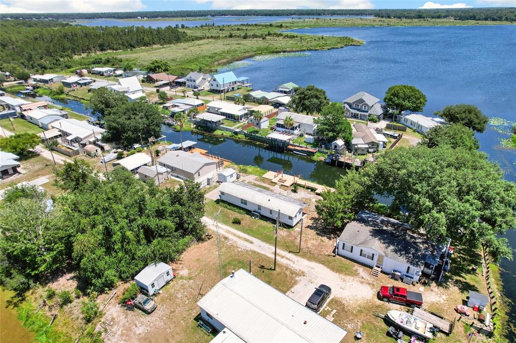 An aerial view shows several houses along a canal leading into a large lake — 13651 NE 237TH COURT, FORT MC COY, FL