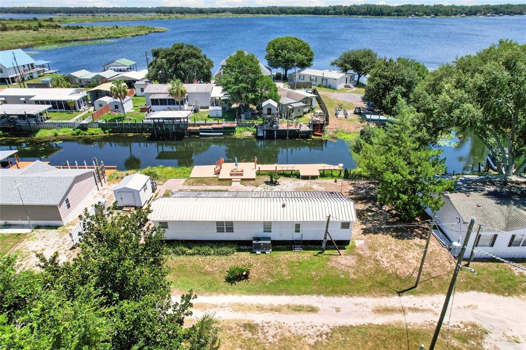 An aerial view shows a mobile home with a metal roof situated along a canal — 13651 NE 237TH COURT, FORT MC COY, FL