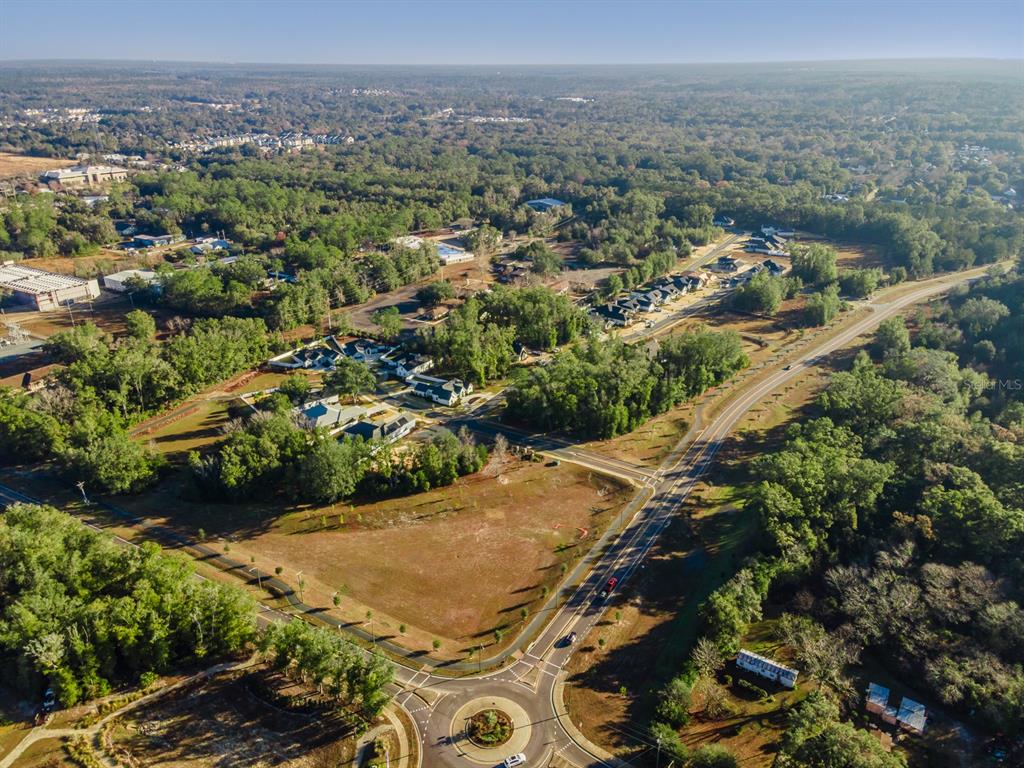 An aerial view shows a vacant, wooded residential lot situated on a curved suburban street — 608 SW 139TH COURT, NEWBERRY, FL
