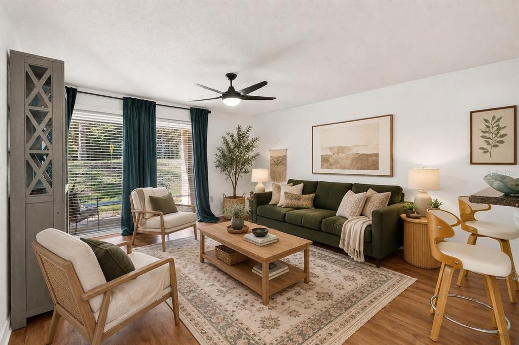 A living room features a green sofa, two armchairs, a coffee table, and sliding glass doors — 1810 NW 23RD BOULEVARD UNIT 230A, GAINESVILLE, FL