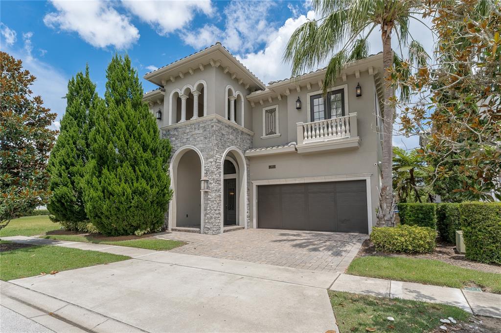A two-story Mediterranean-style house with a stone facade, a balcony, and a two-car garage — 600 MUIRFIELD LOOP, REUNION, FL