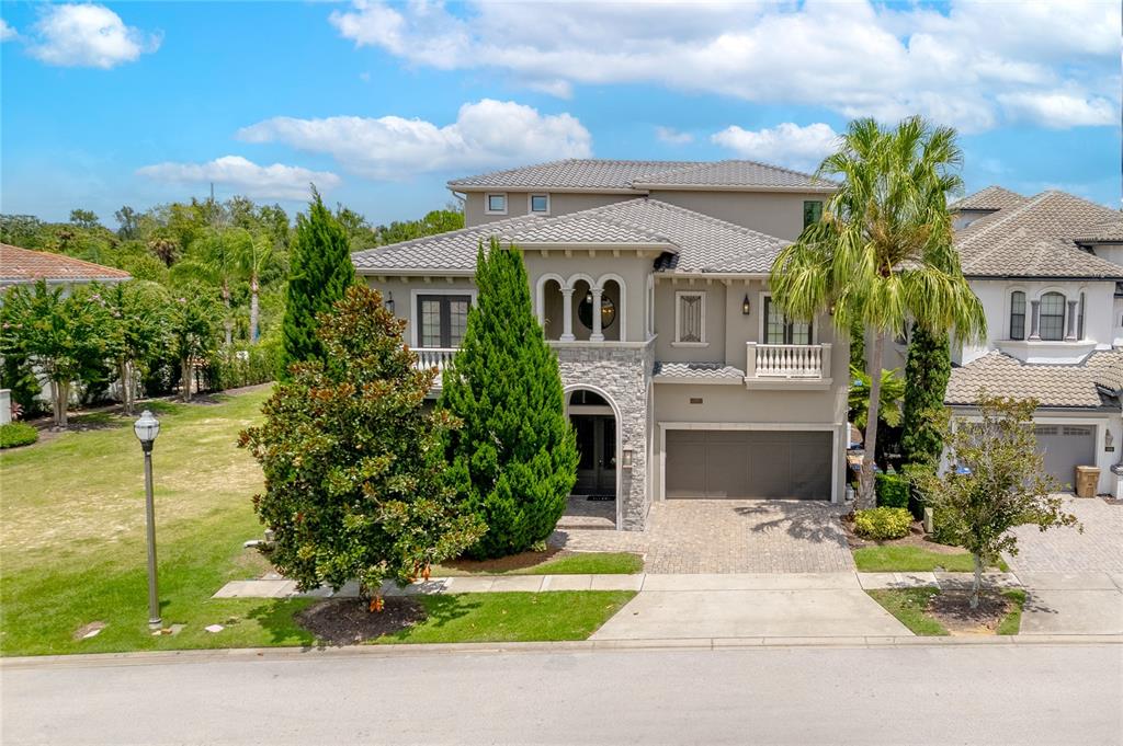 A two-story house with a stone facade, arched entryway, and a paved driveway — 600 MUIRFIELD LOOP, REUNION, FL
