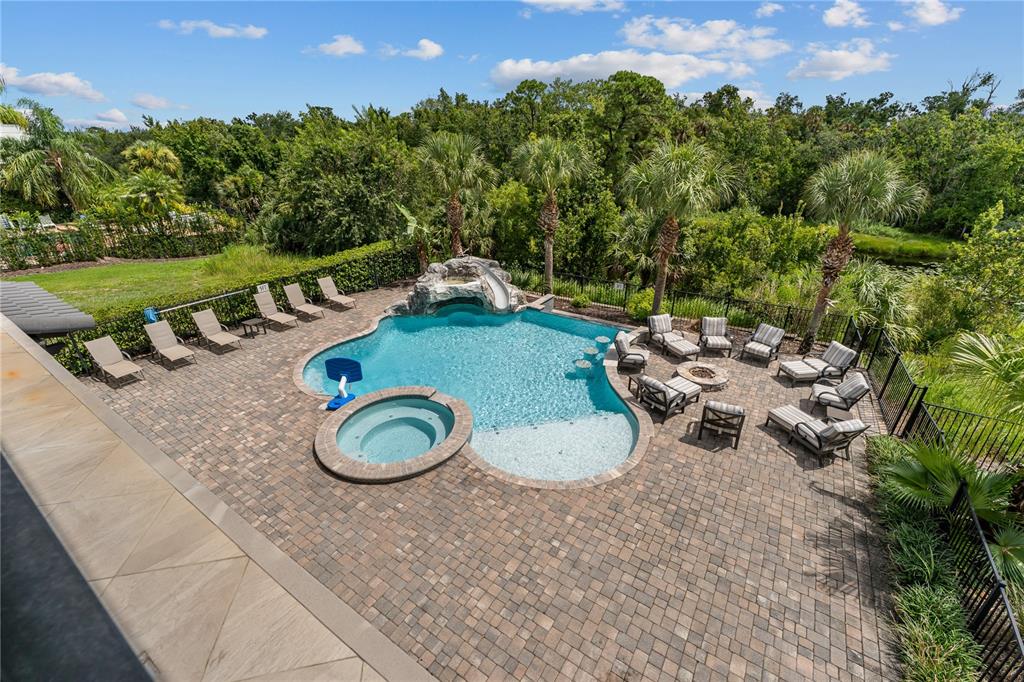An elevated view of a backyard pool area with a hot tub, slide, and patio furniture — 600 MUIRFIELD LOOP, REUNION, FL