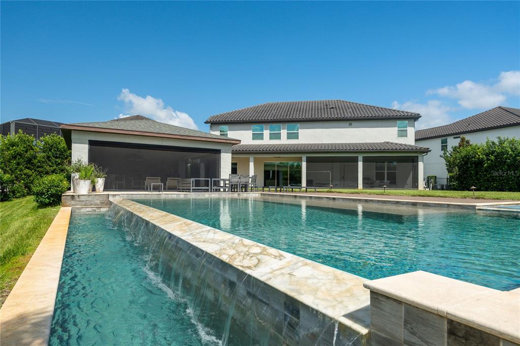 A backyard features a swimming pool with a waterfall edge and a covered patio area — 8192 LUDINGTON CIRCLE, ORLANDO, FL