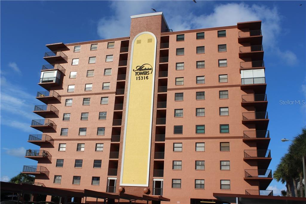 A multi-story, peach-colored residential building features balconies on the left and right sides — 15316 GULF BOULEVARD UNIT 604, MADEIRA BEACH, FL