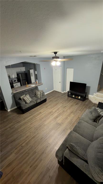 A living room with gray walls, wood-look flooring, two gray sofas, and an open kitchen — 5031 SUNRIDGE PALMS DRIVE, TAMPA, FL