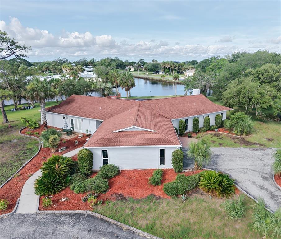 An aerial view of a white single-story house with a red roof near water — 11580 W DIXIE SHORES DRIVE, CRYSTAL RIVER, FL