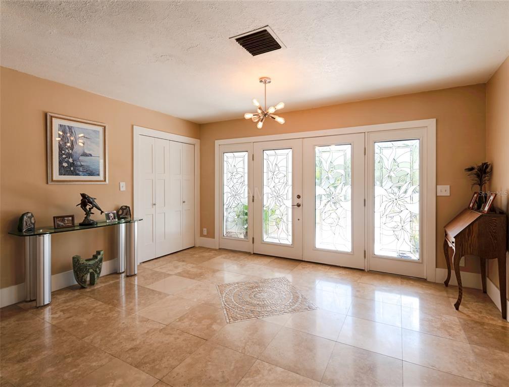 An entryway features tan tile flooring, a modern chandelier, and glass-paneled double doors with sidelights — 11580 W DIXIE SHORES DRIVE, CRYSTAL RIVER, FL