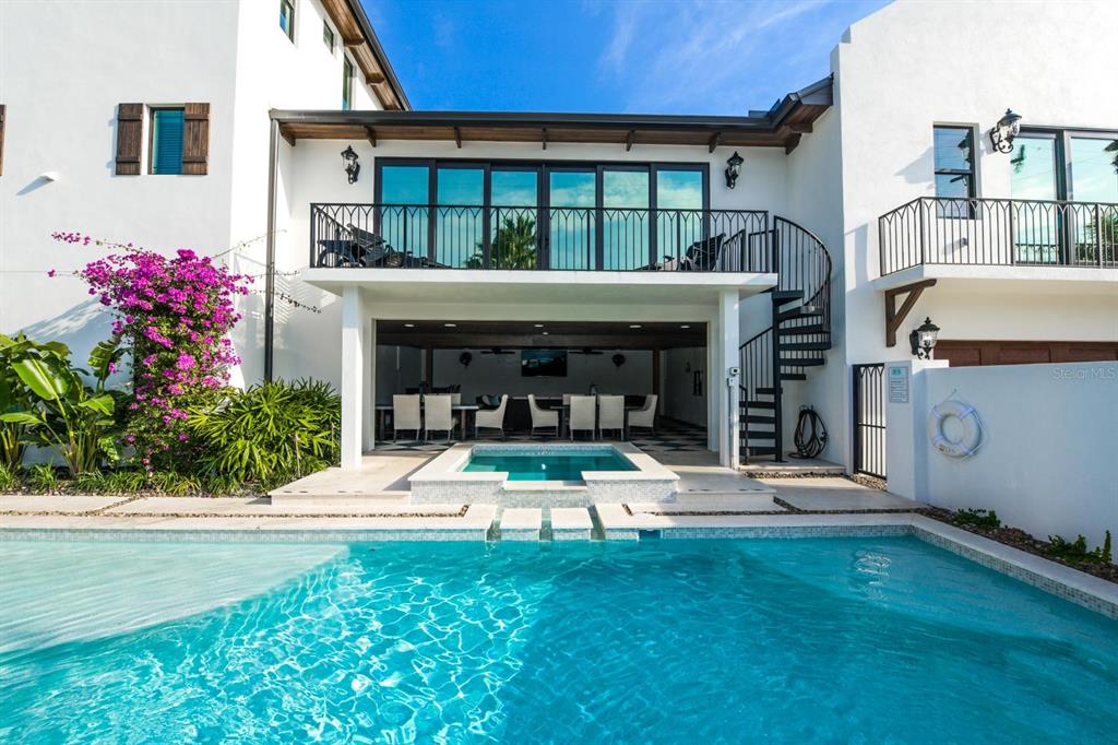 A swimming pool and spa sit in front of a two-story home with a balcony — 340 JACKSON DRIVE, SARASOTA, FL