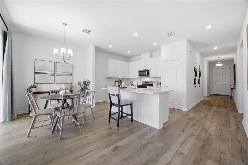 A bright kitchen and dining area with white cabinetry, a center island, and wood flooring — 5731 HIAWASSEE ROAD, LEESBURG, FL